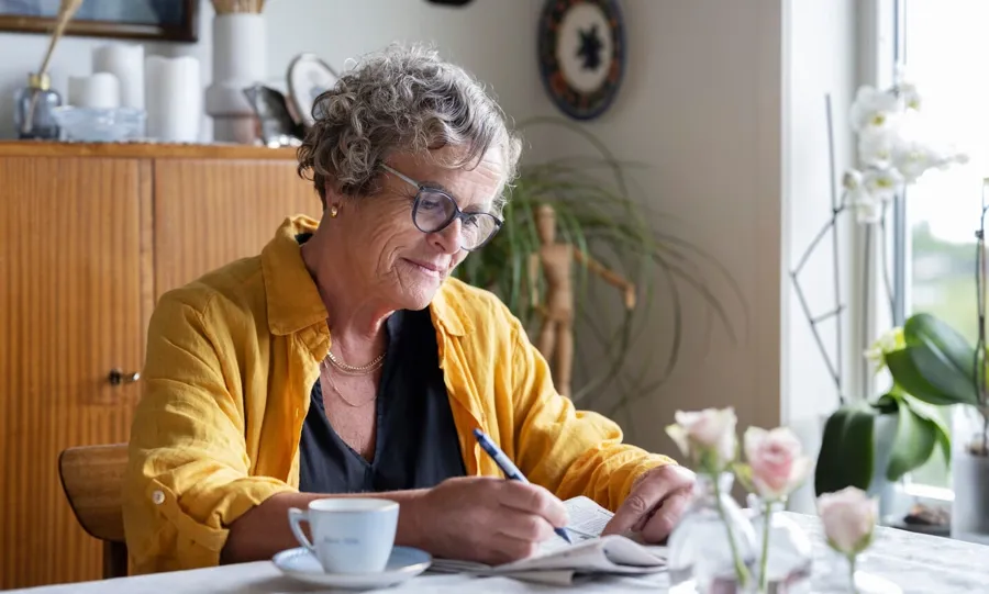 Image de Gullborg assise à sa table avec un café et un journal. Les problèmes urinaires ne sont pas rares chez les personnes atteintes de sclérose en plaques. Dans les faits, plus de 4 personnes sur 5 atteintes de sclérose en plaques sont touchées par des problèmes de continence à un moment ou à un autre de leur vie. 
