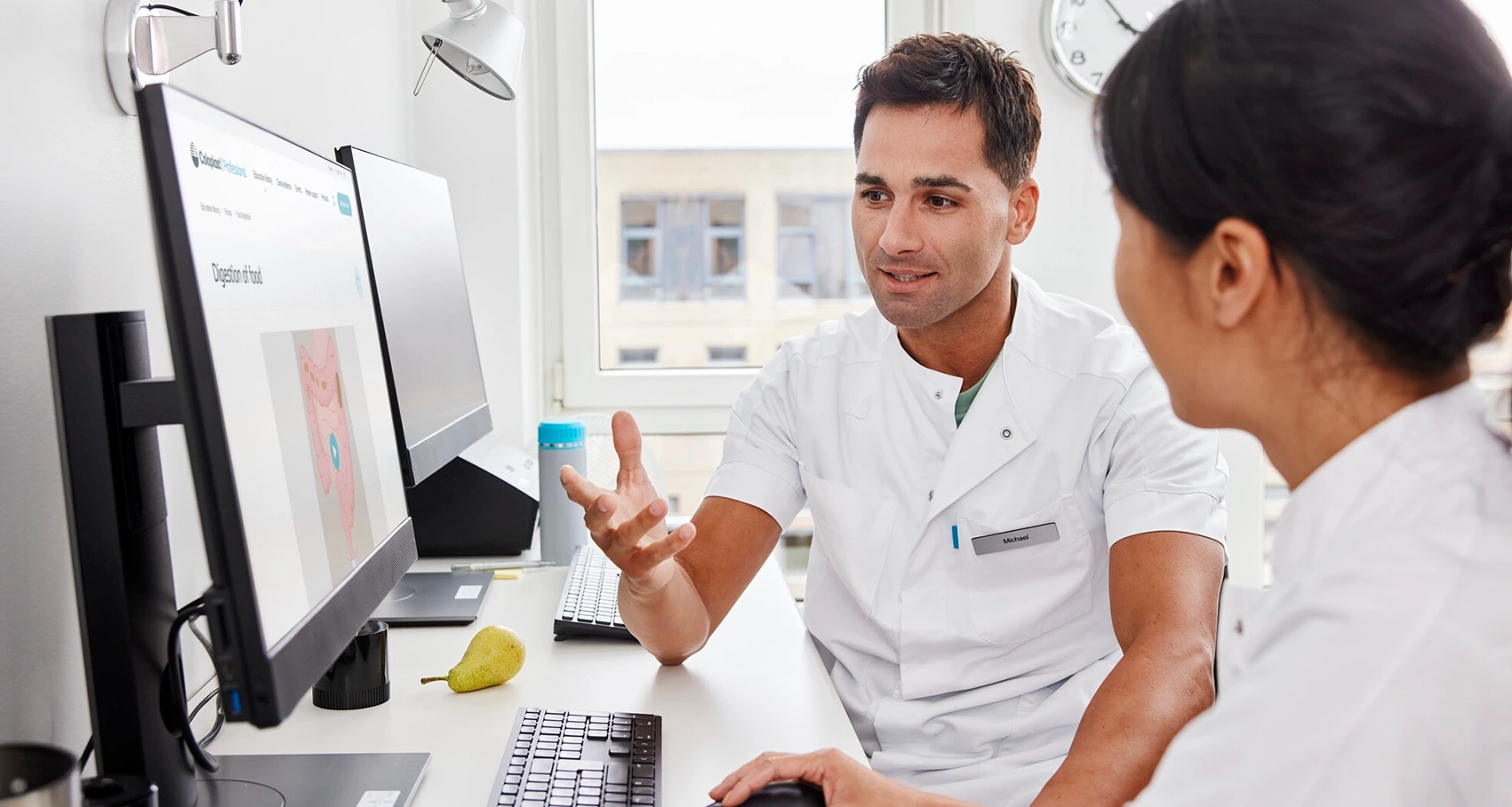 Photo de deux professionnels de santé assis devant un ordinateur. La sclérose en plaques peut entraîner des dysfonctionnements intestinaux. Il existe plusieurs traitements permettant de traiter et de gérer les symptômes. 