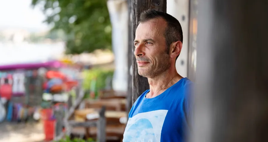 Photo portrait d'André à l'extérieur. Le sondage urinaire intermittent nécessite un processus d’éducation. Au fil du temps, André a appris à se sonder lors de ses déplacements et a développé sa propre routine personnalisée, adaptée à ses besoins. 