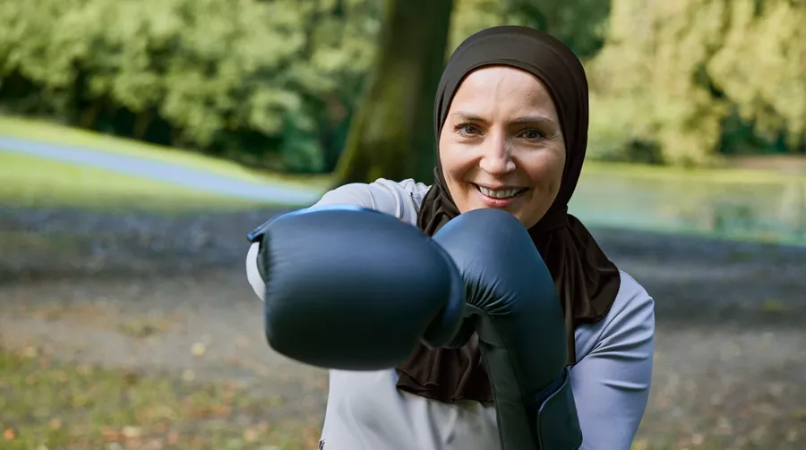 Photo de Fikra dans un parc, s'entraînant avec des gants de boxe. Maintenant que Fikria contrôle mieux son transit, elle peut faire les exercices qu'elle souhaite et se sent plus confiante.   