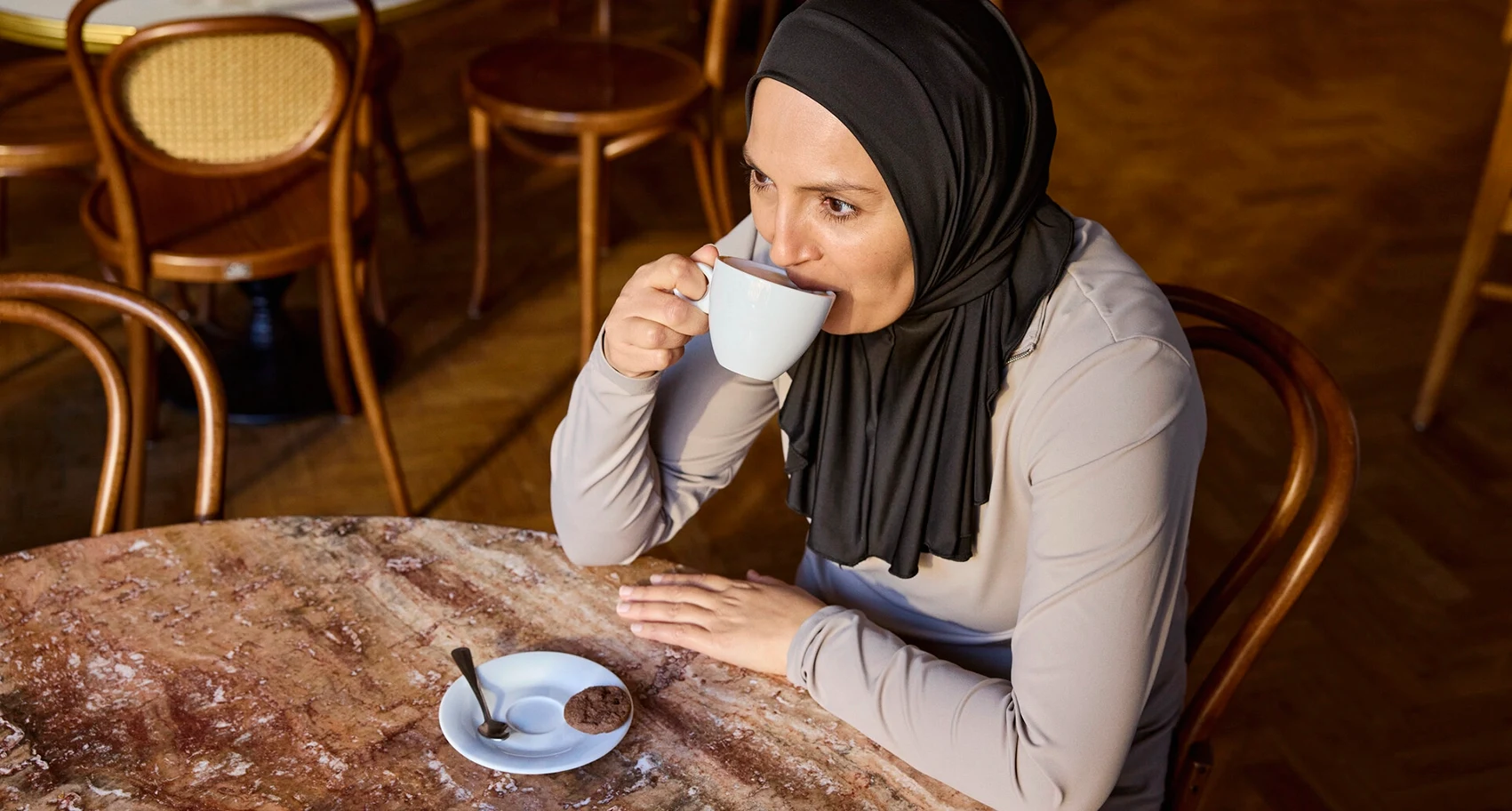 Portrait de Fikria assise dans un café. Fikria vit avec la SEP et les problèmes intestinaux font partie de sa vie. Elle a trouvé la solution qui lui convenait pour gérer ses symptômes. 