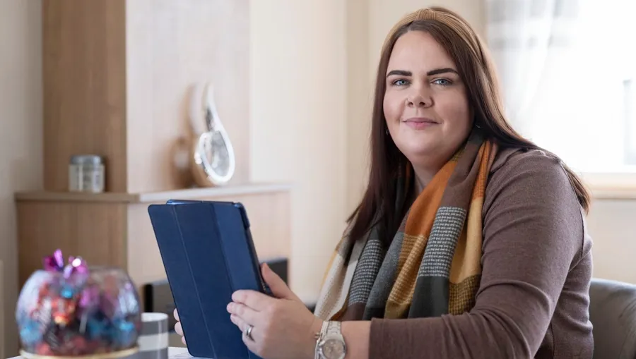 Photo de Sarah assise à une table. C'est quatre ans après son diagnostic initial que Sarah a fait le lien entre ses troubles urinaires et sa SEP. 