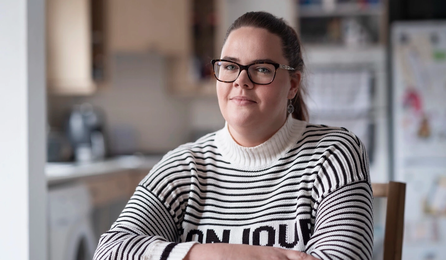 Sarah, utilisatrice de sonde urinaire atteinte de sclérose en plaques, est assise à une table. 
