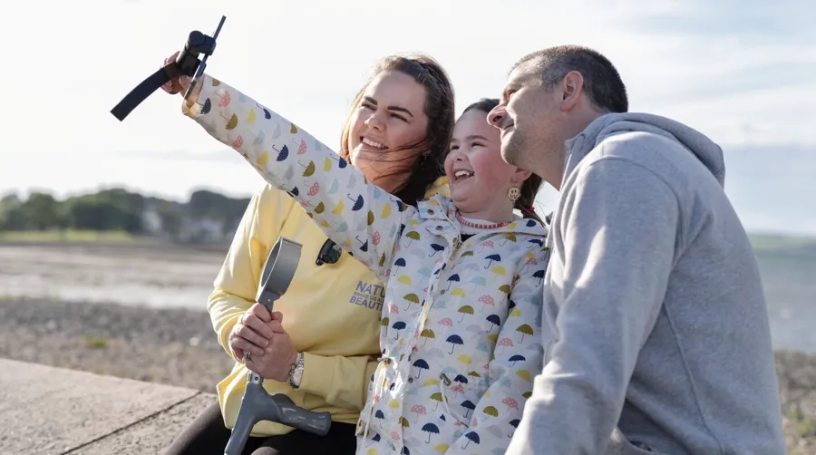 Photo de Sarah et de sa famille prenant un selfie ensemble à la plage. Il a fallu beaucoup de temps à Sarah pour faire le lien entre ses troubles urinaires et son diagnostic de SEP. 